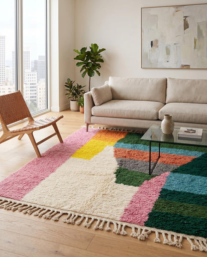 A colorful abstract Moroccan rug by NURA with bold pink and green blocks, styled in a bright, contemporary living room setting.