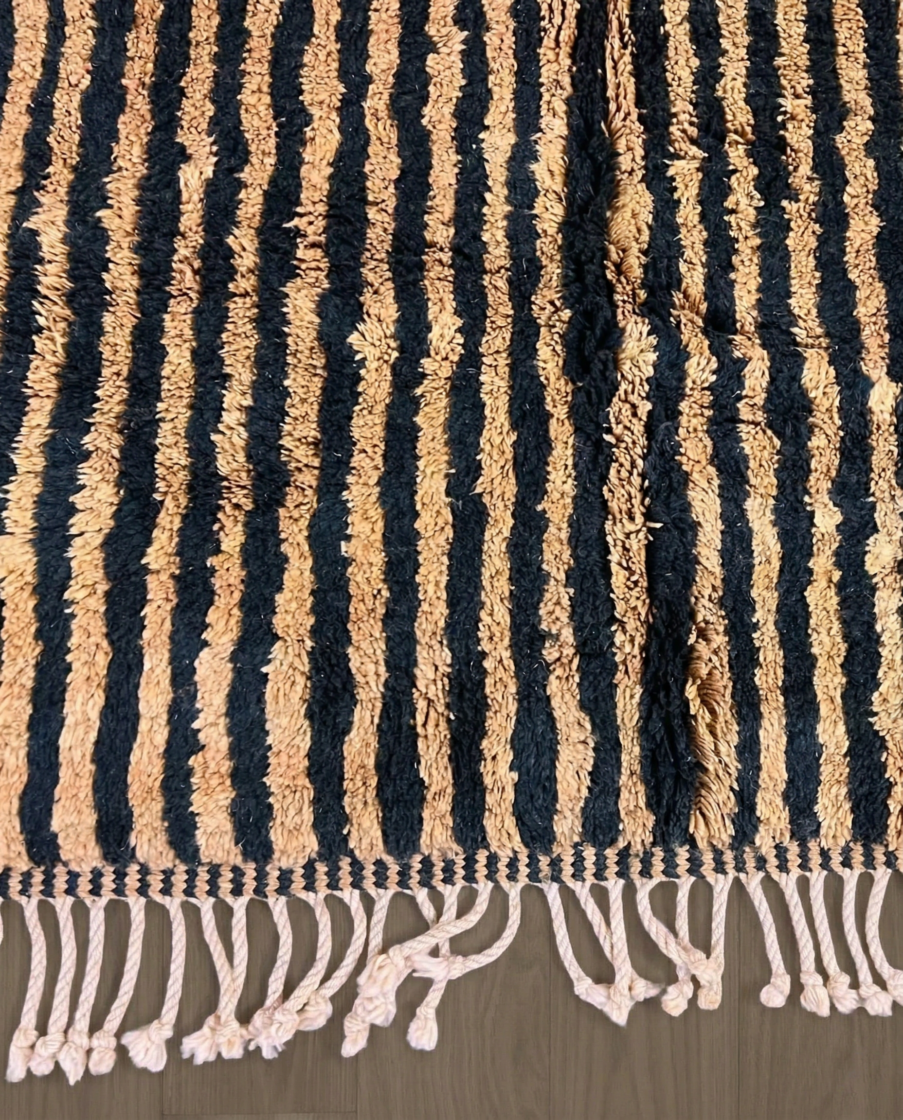 NABILA Beni Ourain black horizontal stripes Moroccan rug close-up of hand-tied fringe and kilim band detail, by NURA