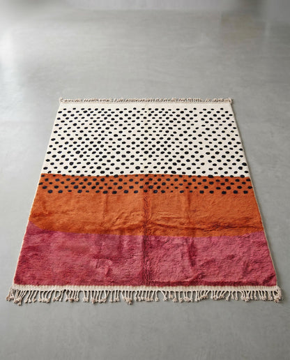 NAFISSA Azilal cream color block dots Moroccan rug displayed on a parquet wood floor, showing full fringe and edge detail, by NURA