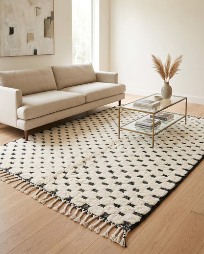A plush cream and black dotted Moroccan rug styled in a bright, modern living room with contemporary furniture by NURA.