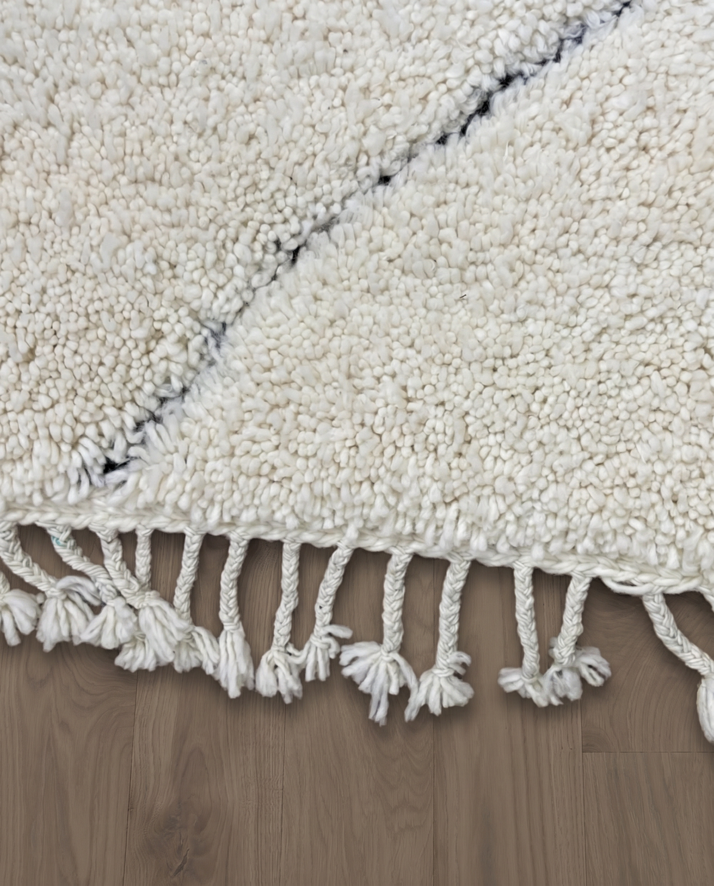 NASSIMA Beni Ourain ivory abstract diamond lattice Moroccan rug close-up of hand-tied fringe and kilim band detail, by NURA