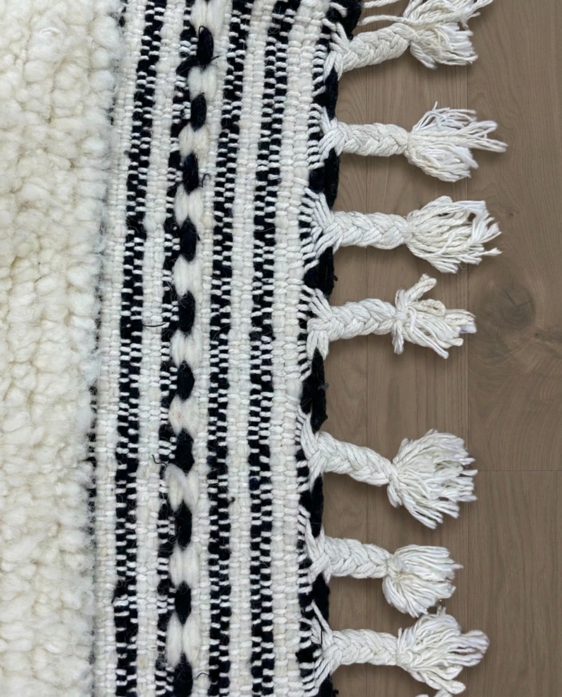 NASSIRA Beni Ourain cream diamond lattice Moroccan rug close-up of hand-tied fringe and kilim band detail, by NURA