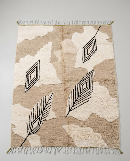 NOURIA Beni Ourain beige floating forms Moroccan rug displayed on a parquet wood floor, showing full fringe and edge detail, by NURA