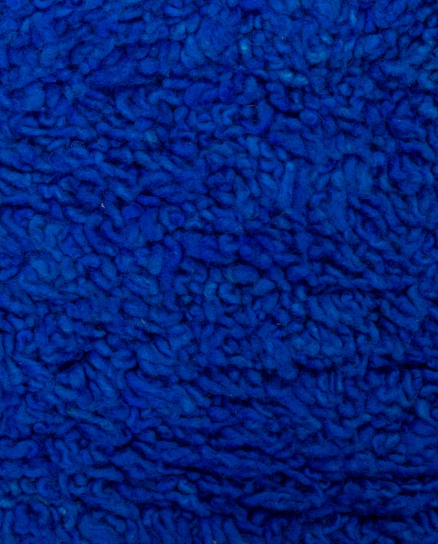 RAJA Mrirt cobalt solid open field Moroccan rug close-up showing hand-knotted wool texture and pile detail, by NURA