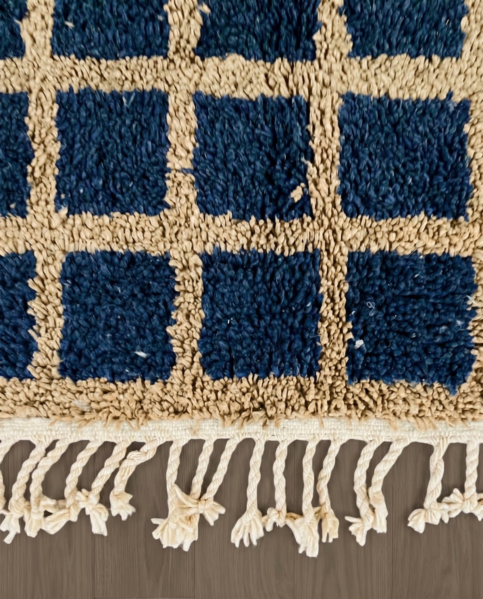 RAMA Beni Ourain navy checker grid Moroccan rug close-up of hand-tied fringe and kilim band detail, by NURA