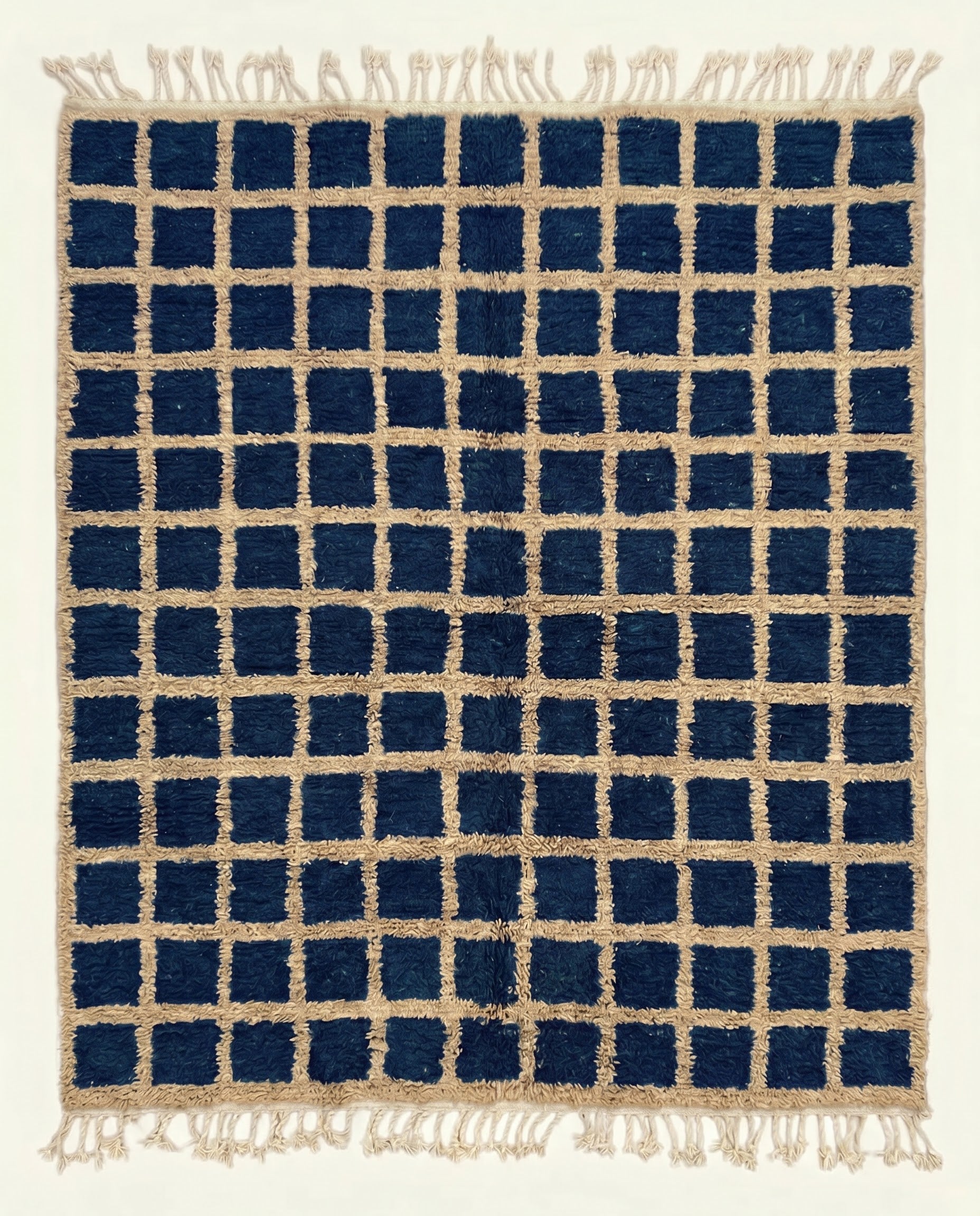 A bold navy checkered Moroccan rug featuring a contrasting beige grid pattern and dense hand-knotted wool pile by NURA.