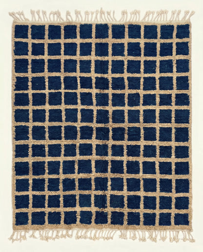 A bold navy checkered Moroccan rug featuring a contrasting beige grid pattern and dense hand-knotted wool pile by NURA.