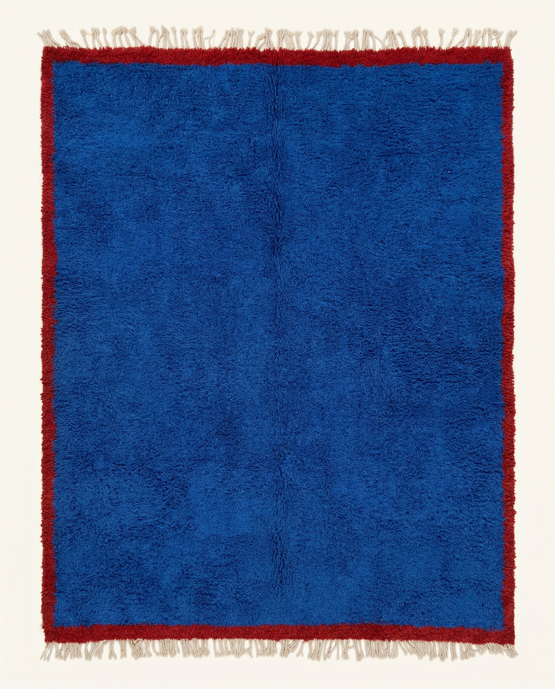 Plush cobalt blue Beni Ourain Moroccan rug with a bold solid cherry red border and natural fringe, by NURA.