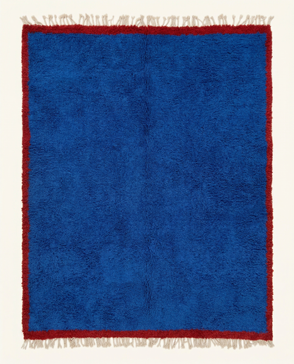 Plush cobalt blue Beni Ourain Moroccan rug with a bold solid cherry red border and natural fringe, by NURA.