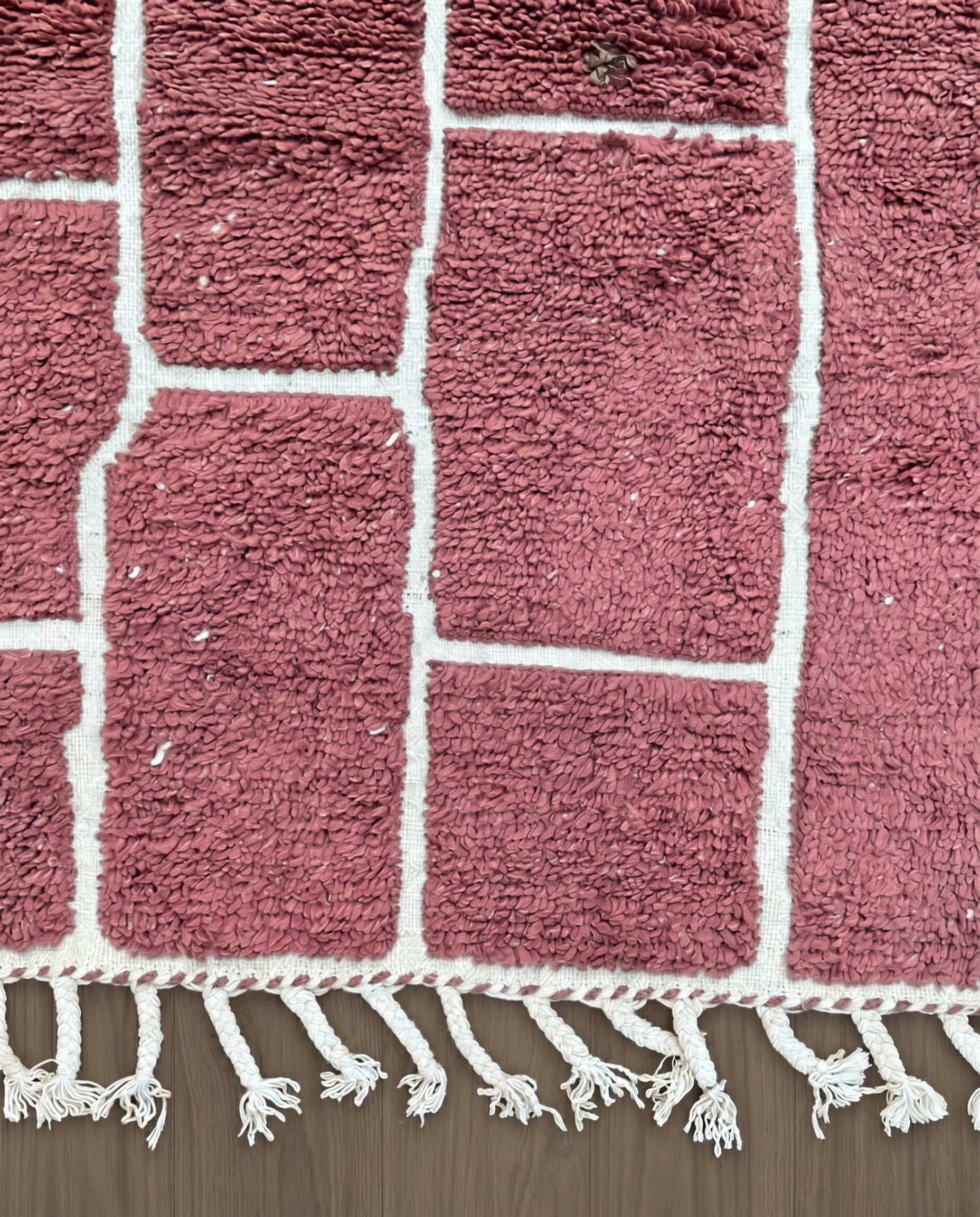 RAZANE Beni Ourain dusty rose irregular block grid Moroccan rug close-up of hand-tied fringe and kilim band detail, by NURA