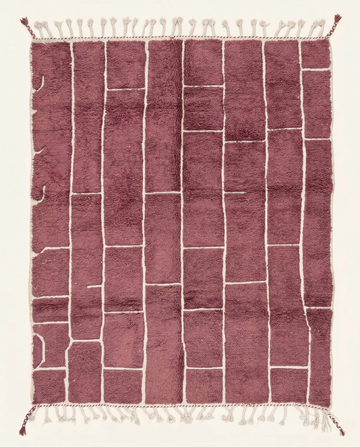 A modern Moroccan rug featuring an irregular block grid in dusty rose with recessed cream lines, showcasing a plush wool pile by NURA.