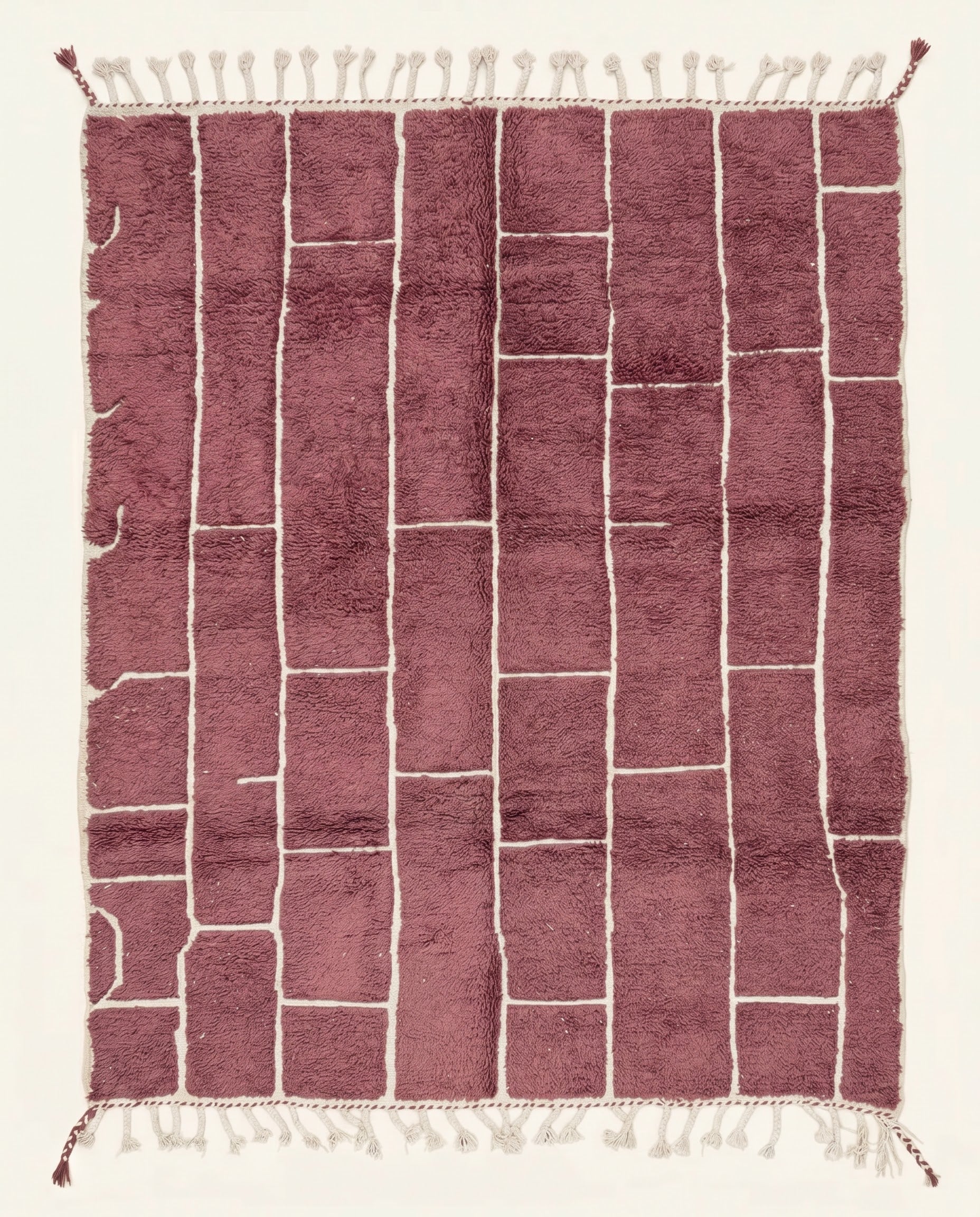A modern Moroccan rug featuring an irregular block grid in dusty rose with recessed cream lines, showcasing a plush wool pile by NURA.