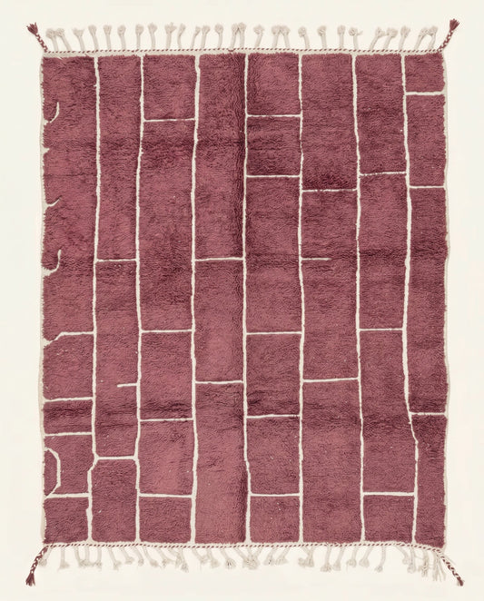 A modern Moroccan rug featuring an irregular block grid in dusty rose with recessed cream lines, showcasing a plush wool pile by NURA.