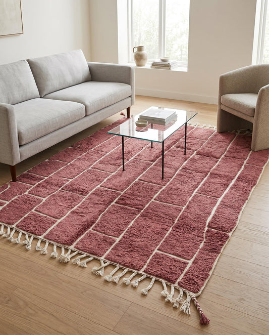 A dusty rose Moroccan rug with an irregular cream block grid, styled in a modern living room setting by NURA.