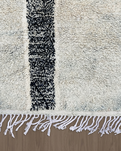 RIHAB Beni Ourain ivory irregular striped field Moroccan rug close-up of hand-tied fringe and kilim band detail, by NURA