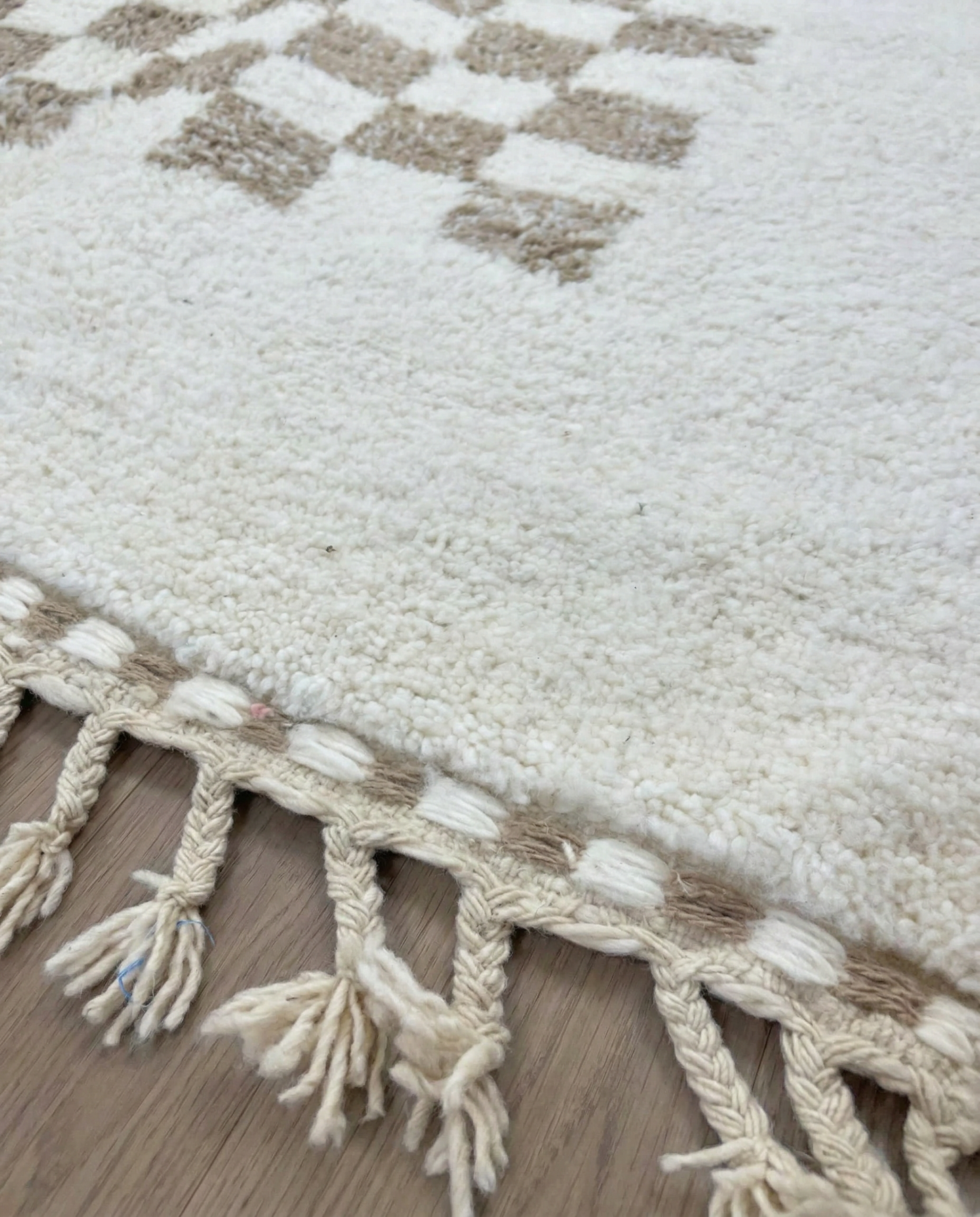 RIMA Beni Ourain cream framed checkerboard Moroccan rug close-up of hand-tied fringe and kilim band detail, by NURA