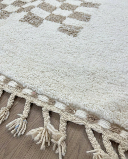 RIMA Beni Ourain cream framed checkerboard Moroccan rug close-up of hand-tied fringe and kilim band detail, by NURA