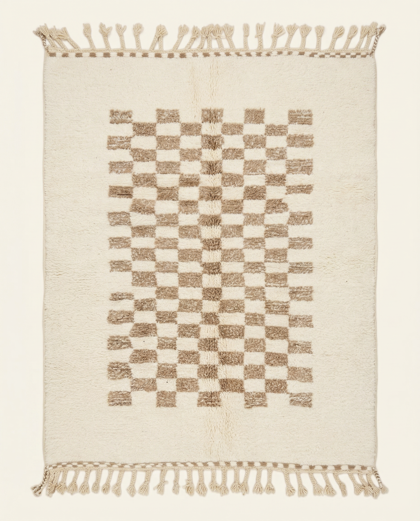 Plush cream Beni Ourain Moroccan rug with a central taupe checkerboard pattern and braided tassels, by NURA.