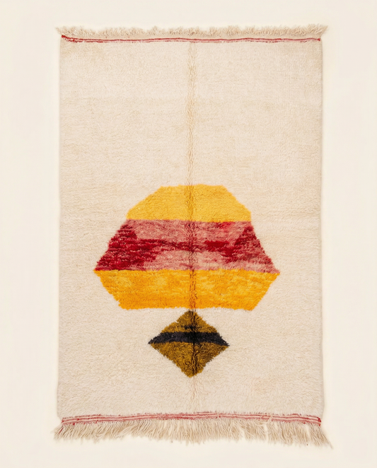 Plush cream Azilal Moroccan rug with a bold abstract central motif in yellow and red, by NURA.