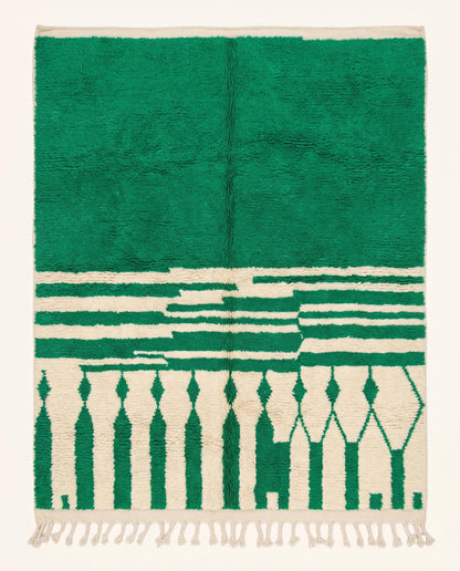 A plush Moroccan wool rug featuring a bold green solid half and a cream half with geometric diamond columns, styled by NURA.