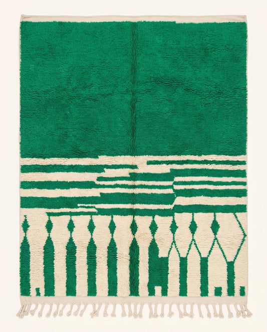 A plush Moroccan wool rug featuring a bold green solid half and a cream half with geometric diamond columns, styled by NURA.