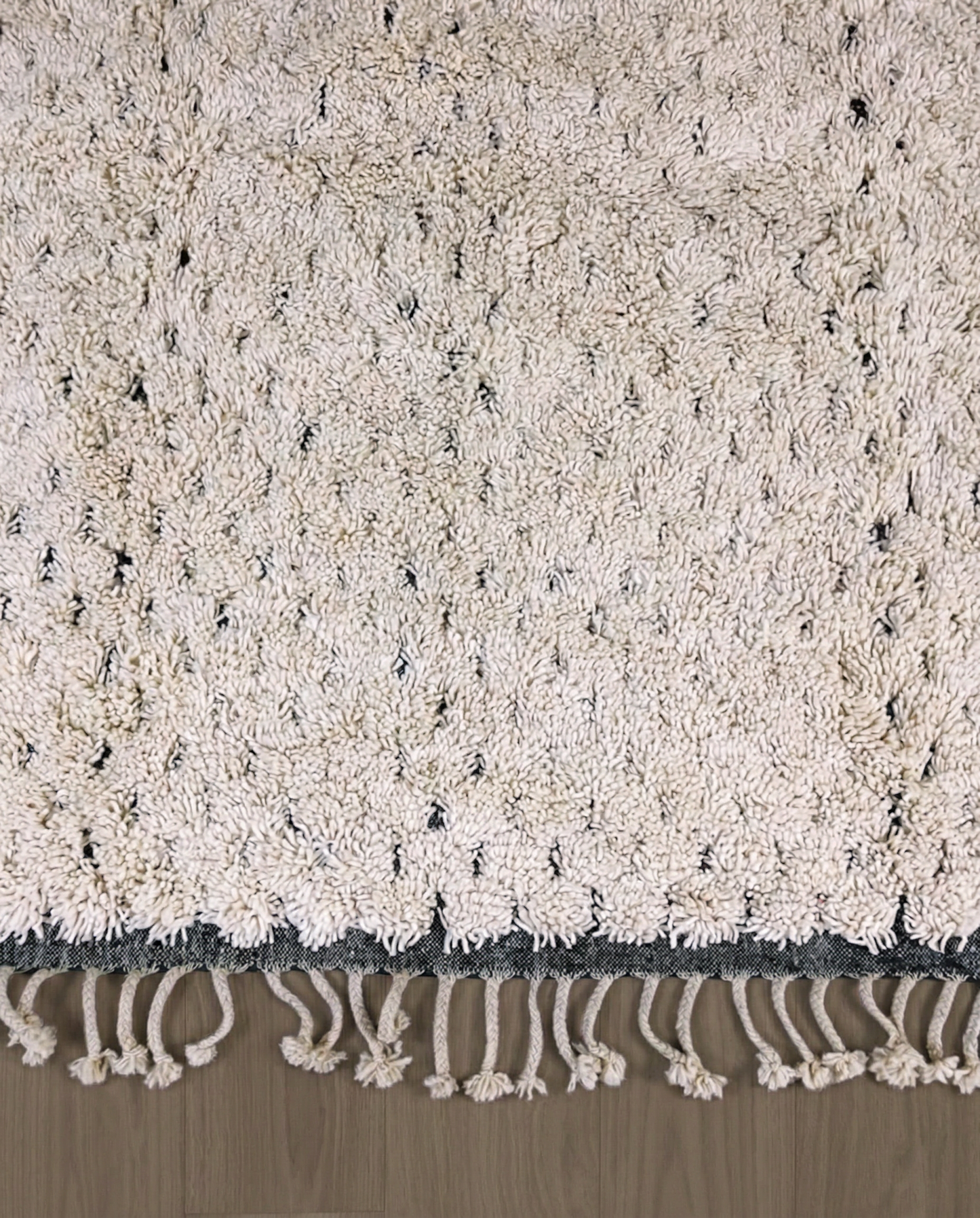 DAMYA Beni Ourain cream dashed line repeat Moroccan rug close-up of hand-tied fringe and kilim band detail, by NURA
