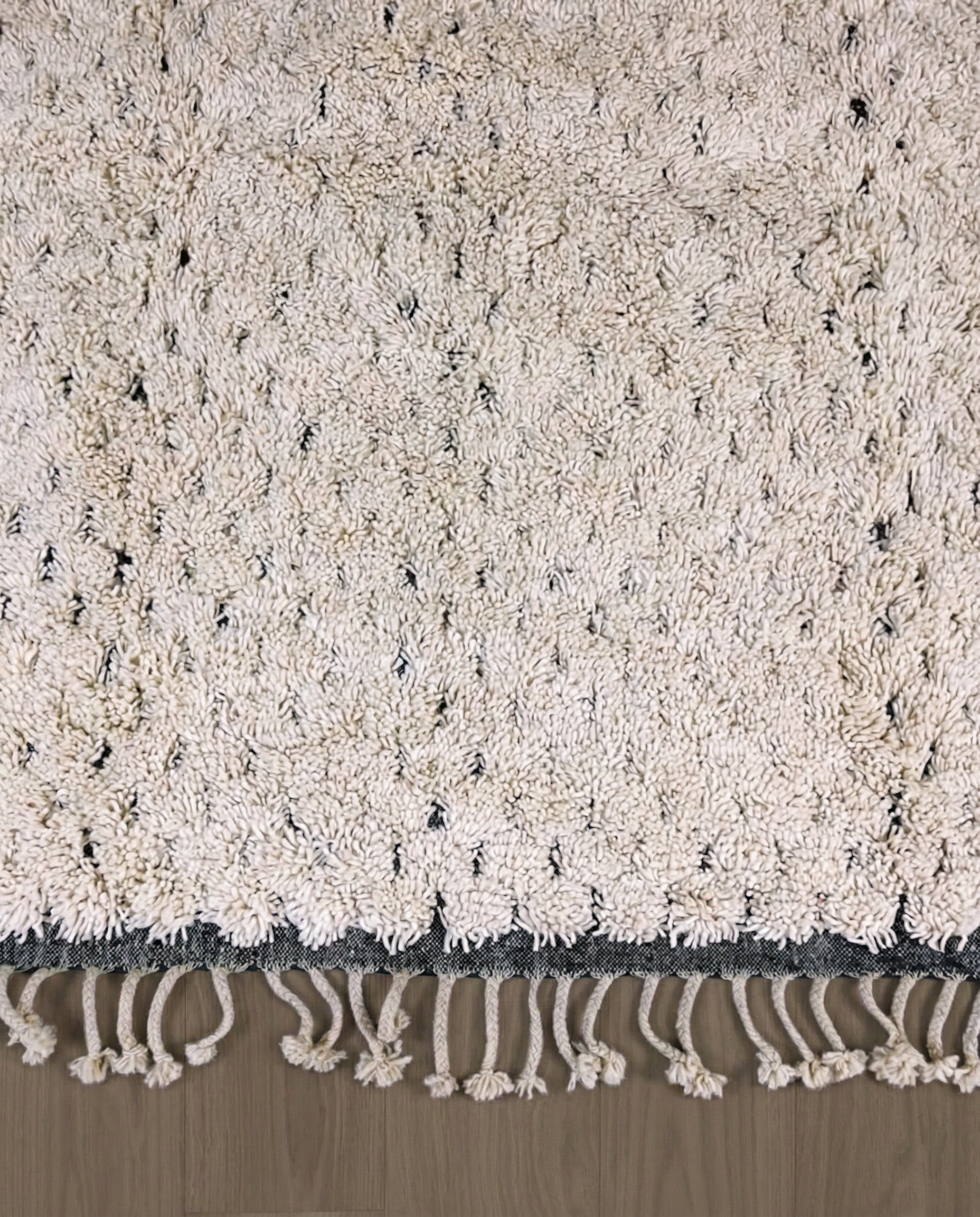 DAMYA Beni Ourain cream dashed line repeat Moroccan rug close-up of hand-tied fringe and kilim band detail, by NURA