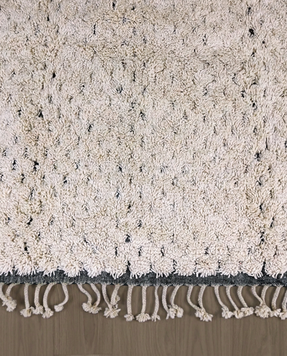DAMYA Beni Ourain cream dashed line repeat Moroccan rug close-up of hand-tied fringe and kilim band detail, by NURA