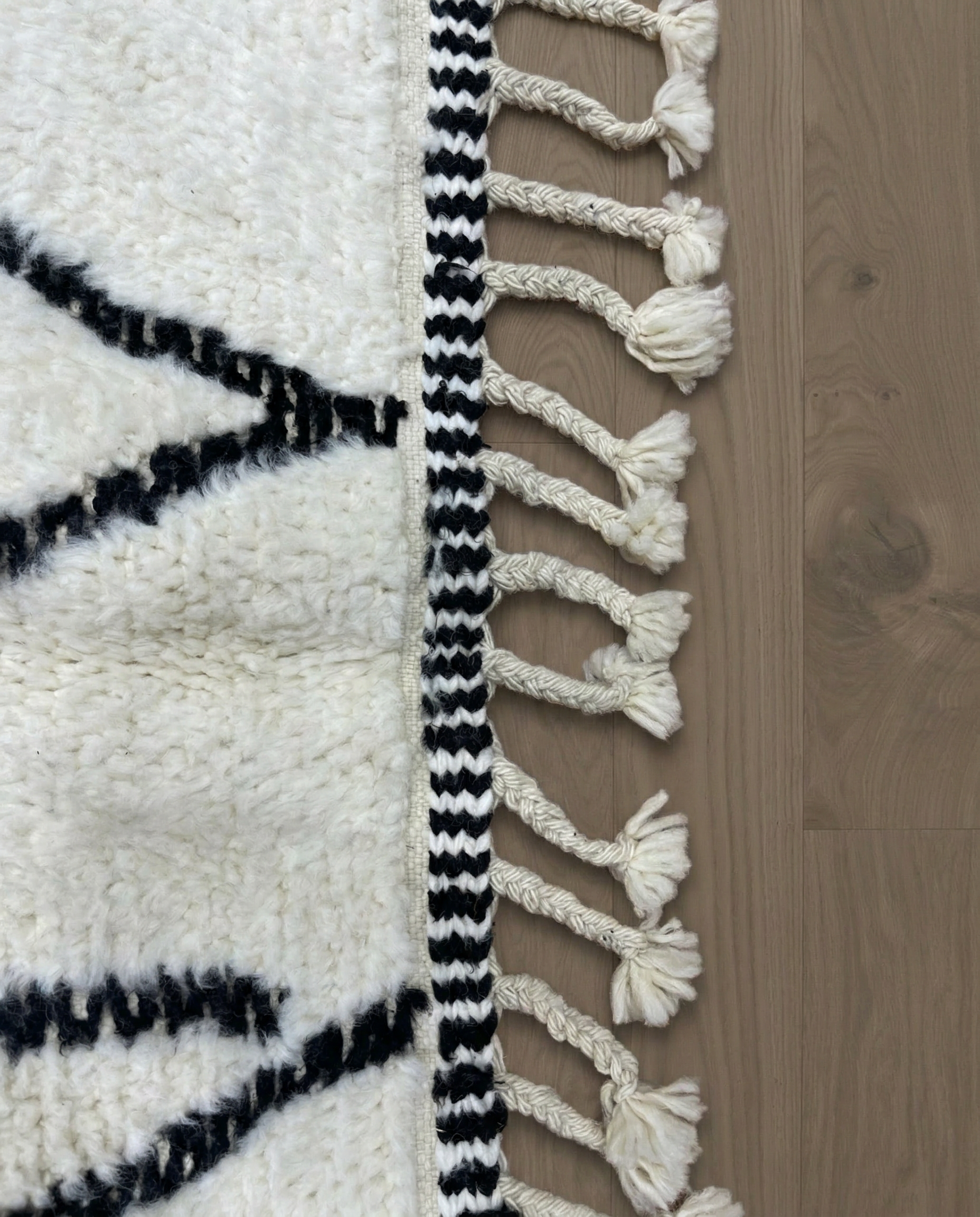 SALIMA Beni Ourain ivory open diamond motif Moroccan rug close-up of hand-tied fringe and kilim band detail, by NURA