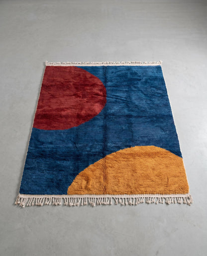 SAMIRA Beni Ourain cobalt bold color block Moroccan rug displayed on a parquet wood floor, showing full fringe and edge detail, by NURA