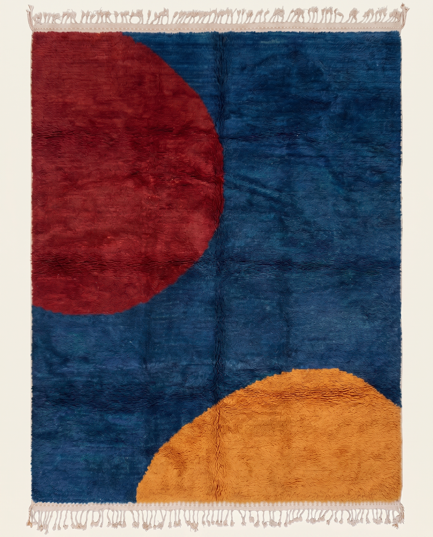 Bold color block Moroccan rug by NURA featuring a plush cobalt blue field with large crimson and ochre abstract circular forms.
