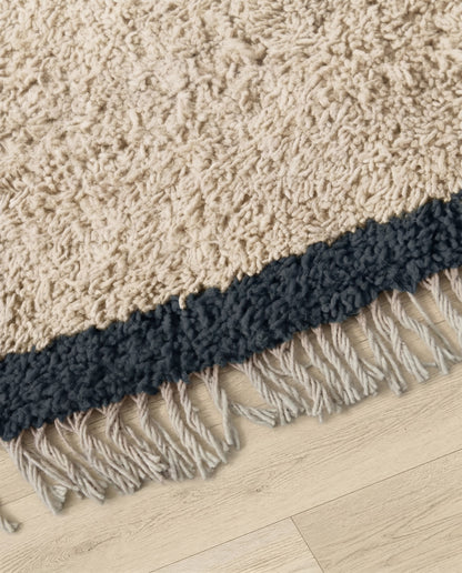SANAA Beni Ourain cream bordered field Moroccan rug close-up of hand-tied fringe and kilim band detail, by NURA