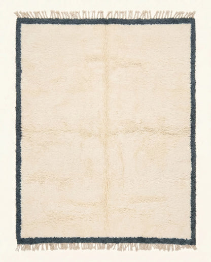 A plush cream Moroccan Beni Ourain rug featuring a thick charcoal border, hand-knotted from soft wool by NURA.