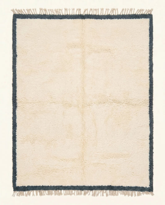 A plush cream Moroccan Beni Ourain rug featuring a thick charcoal border, hand-knotted from soft wool by NURA.