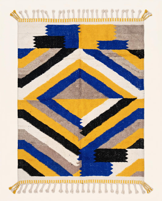 A striking Moroccan flatweave rug by NURA featuring bold concentric chevrons in mustard yellow, cobalt blue, black, and white.