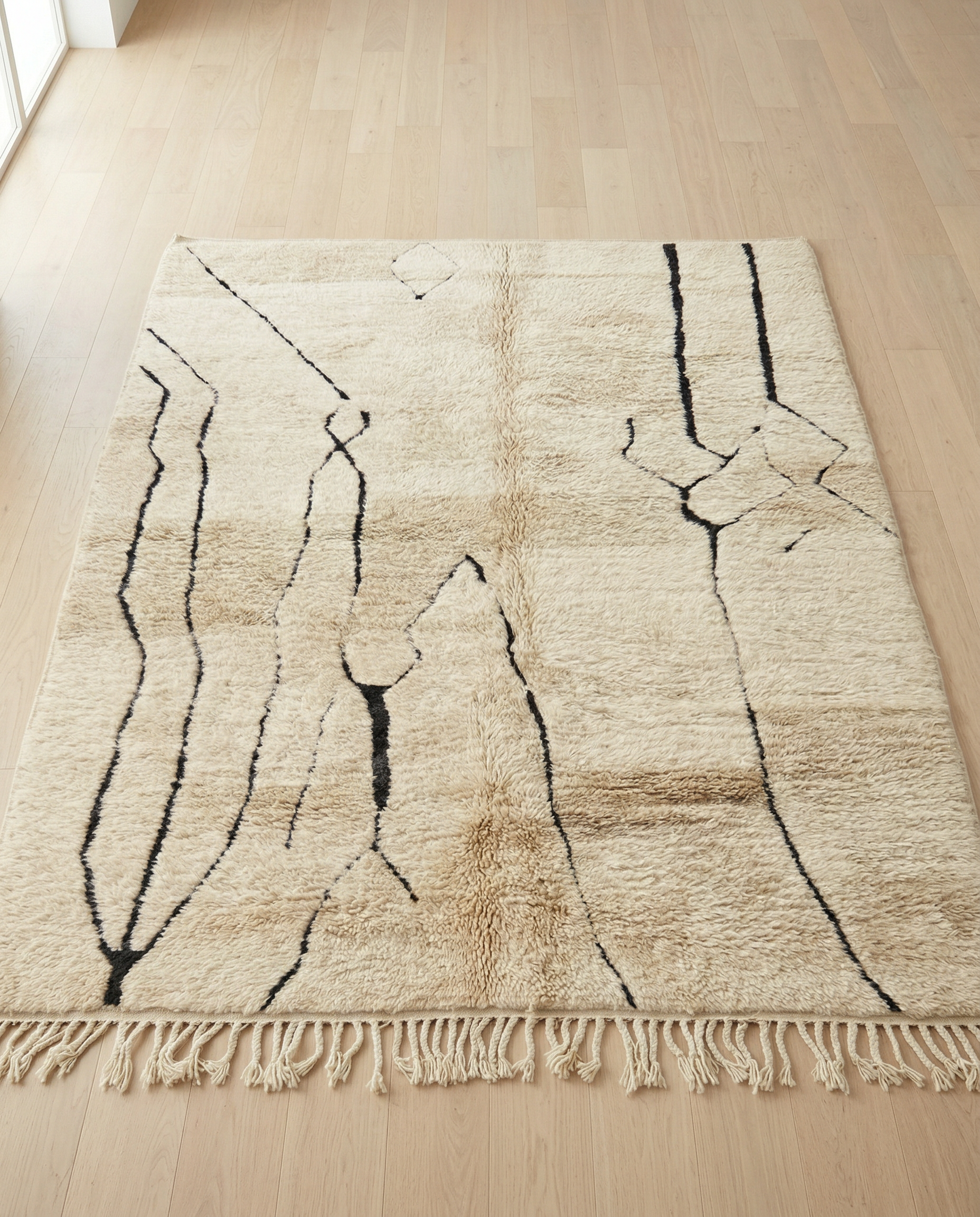 SOFIA Mrirt beige organic abstract Moroccan rug displayed on a parquet wood floor, showing full fringe and edge detail, by NURA