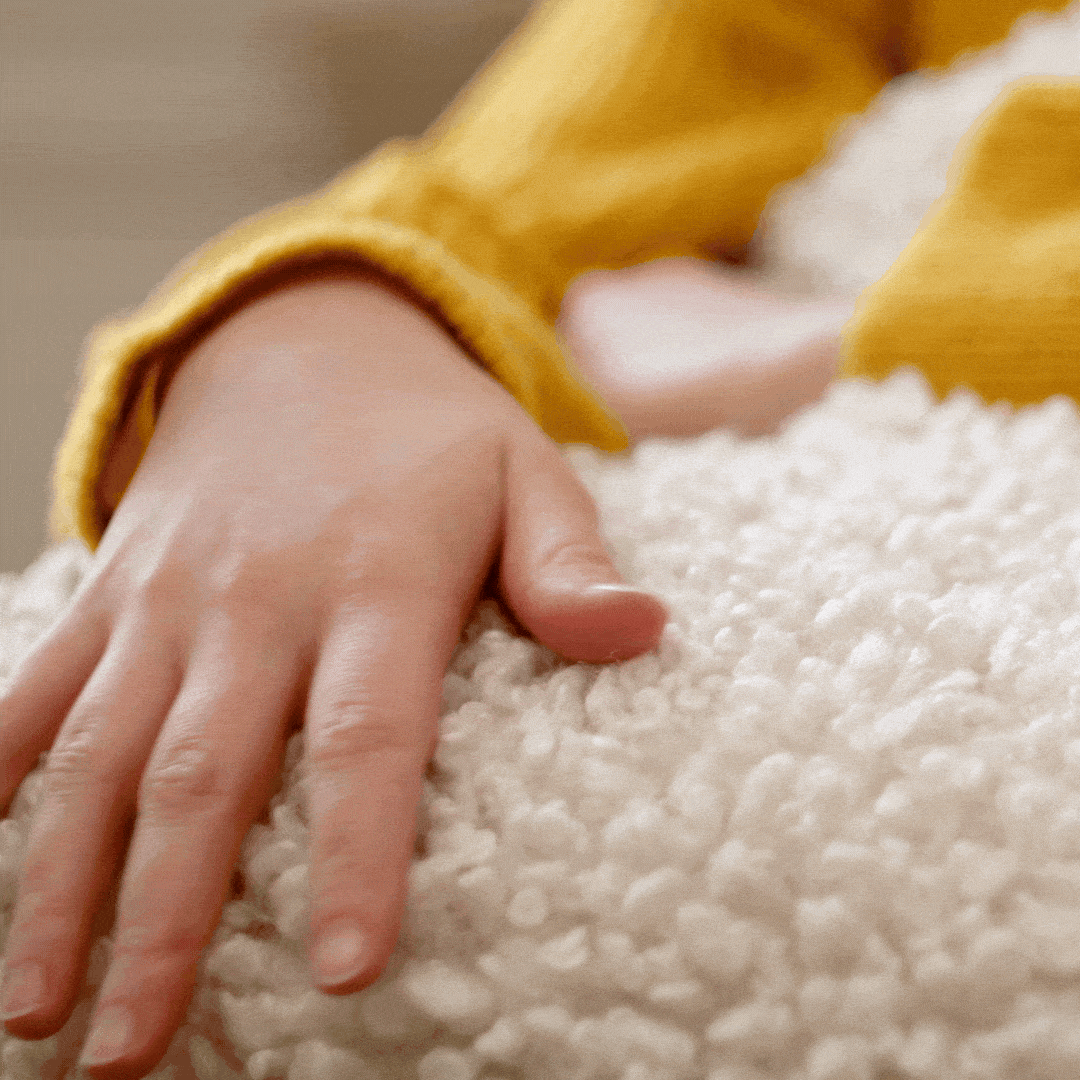 Hand softly gliding over a plush white Moroccan wool rug, highlighting the natural softness and rich texture of NURA hand-knotted wool rugs.