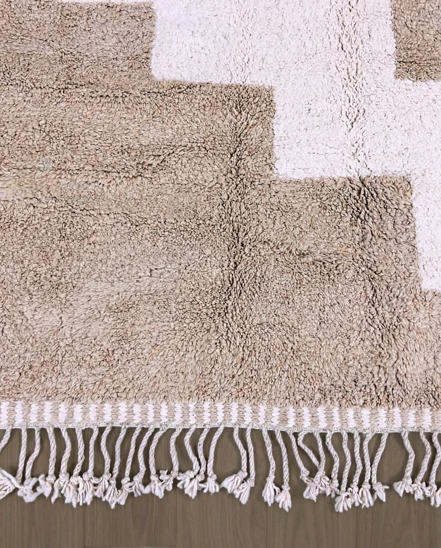 SOUMAYA Beni Ourain cream abstract stepped blocks Moroccan rug close-up of hand-tied fringe and kilim band detail, by NURA