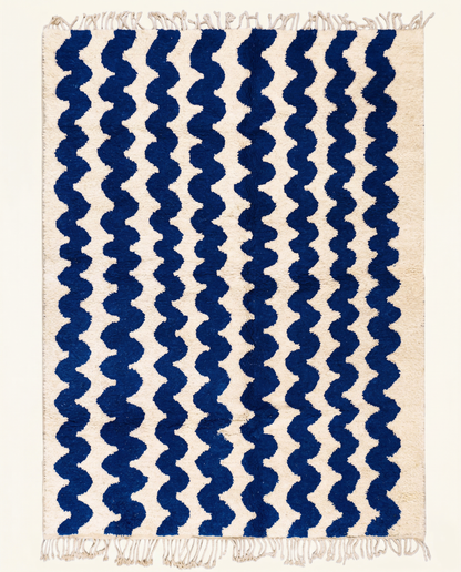 Plush cream Moroccan rug with a bold all-over pattern of wavy cobalt blue horizontal stripes and a thick pile, by NURA.