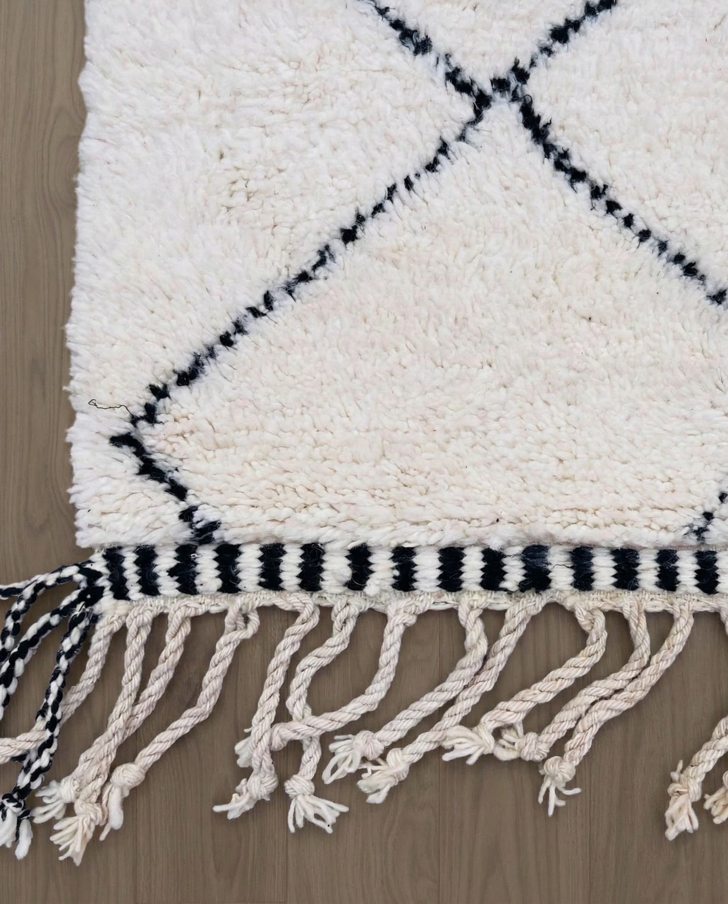 WAFAA Beni Ourain cream diamond lattice Moroccan rug close-up of hand-tied fringe and kilim band detail, by NURA