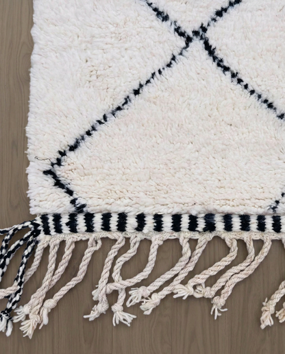 WAFAA Beni Ourain cream diamond lattice Moroccan rug close-up of hand-tied fringe and kilim band detail, by NURA
