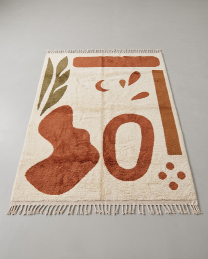 WIDAD Azilal cream organic abstract Moroccan rug displayed on a parquet wood floor, showing full fringe and edge detail, by NURA