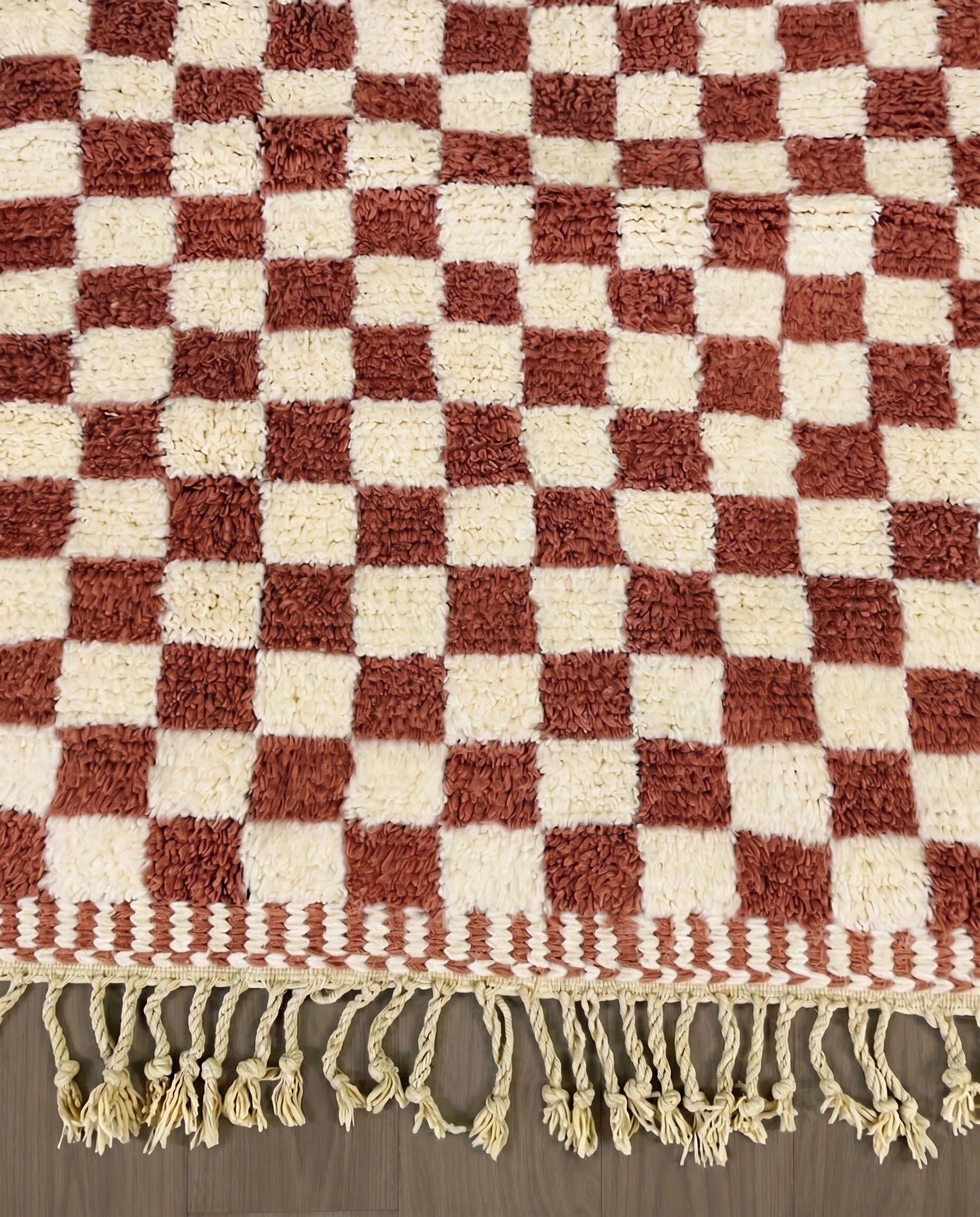 ZAHIA Beni Ourain terracotta checker grid Moroccan rug close-up of hand-tied fringe and kilim band detail, by NURA