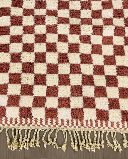 ZAHIA Beni Ourain terracotta checker grid Moroccan rug close-up of hand-tied fringe and kilim band detail, by NURA