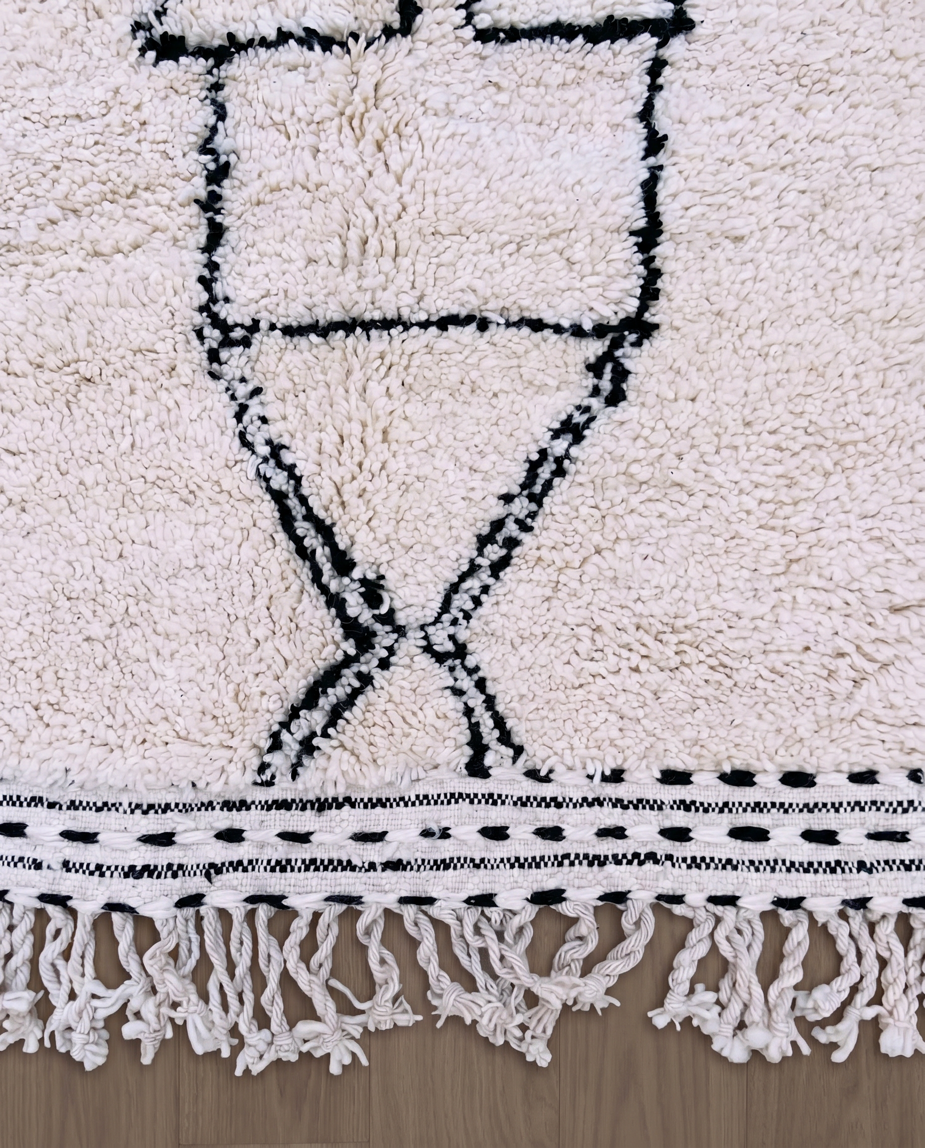 ZAINA Beni Ourain ivory panelled checkerboard Moroccan rug close-up of hand-tied fringe and kilim band detail, by NURA