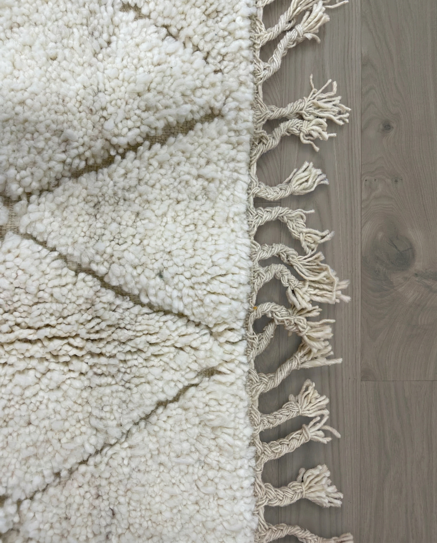 ZAKIA Beni Ourain ivory diamond lattice Moroccan rug close-up of hand-tied fringe and kilim band detail, by NURA