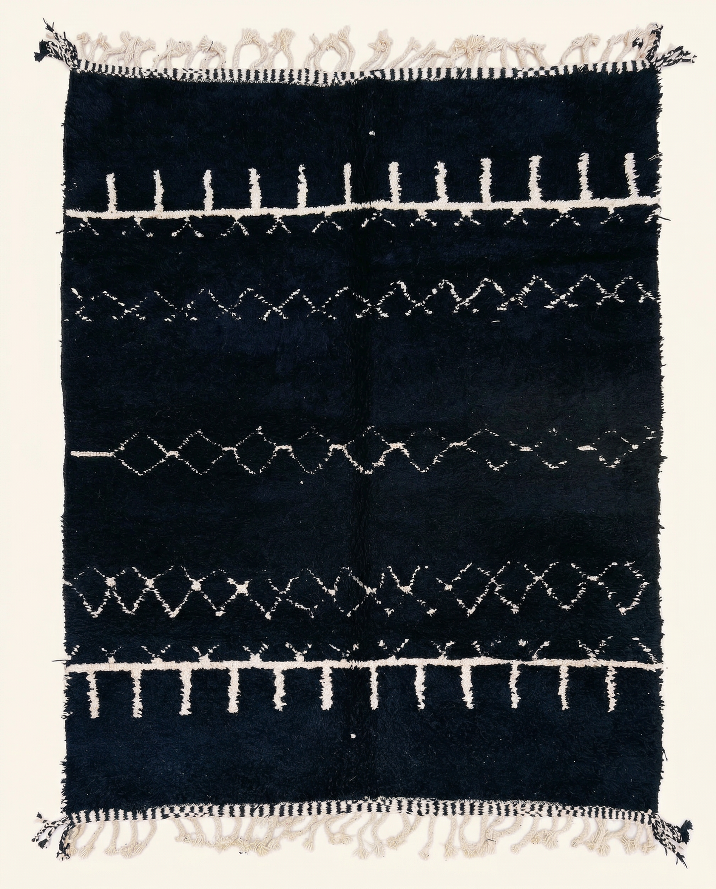 Plush black Beni Ourain Moroccan rug with horizontal white geometric bands and a thick pile, by NURA.