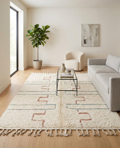 Plush cream Beni Ourain Moroccan rug with blush and blue geometric motifs styled in a bright, modern living room by NURA.
